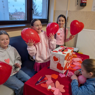 Uczennice przy poczcie walentynkowej, trzymają czerwone balony