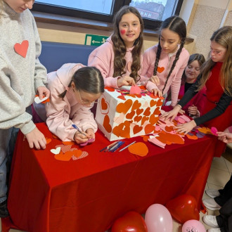 Uśmiechnięte uczennice przy pudełku walentynkowym