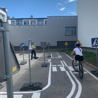 dziewczynka jedzie na rowerze po placu manewrowym