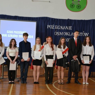 Uśmiechnięci ósmoklasiści odbierający stypendium za działalność społeczną