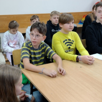 Uczeń klasy piątej podczas wypowiedzi, w tle inni uczniowie