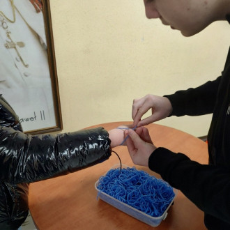 Uczeń wiąże sznurek na nadgarstku koleżanki