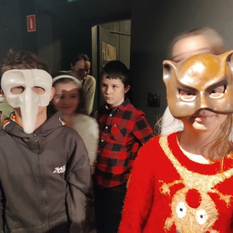 Uśmiechnięci uczniowie w maskach teatralnych